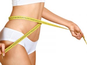 foto aproximada de barriga feminina com fita métrica em volta e fundo branco
